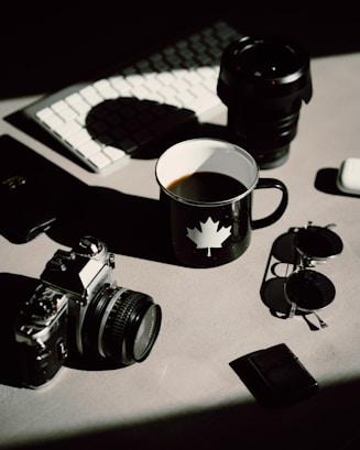 black dslr camera beside black ceramic mug on table