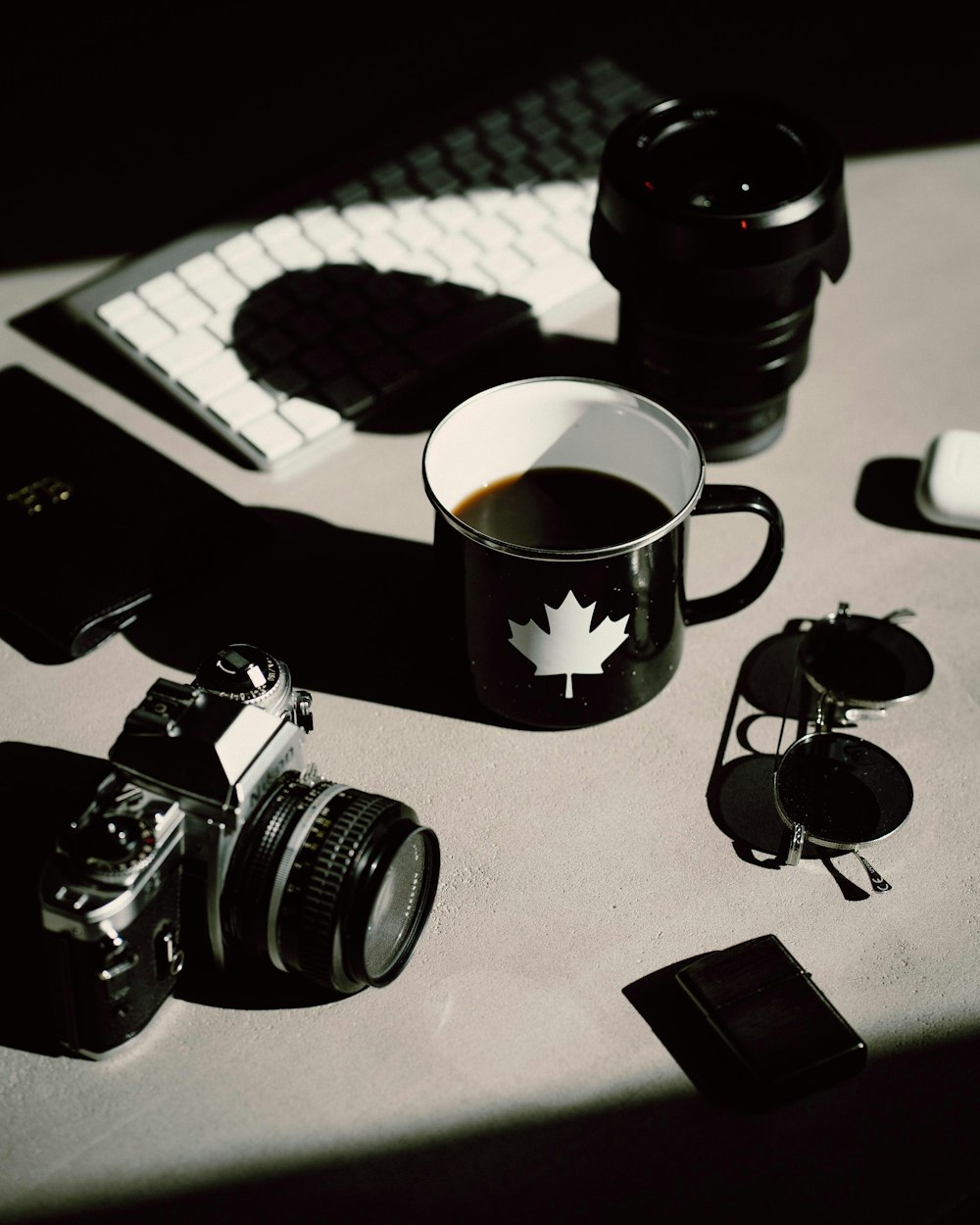 Cámara DSLR negra junto a taza de cerámica negra sobre mesa