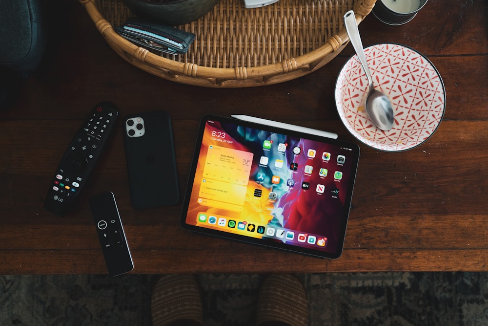 black iphone 5 beside black remote control on brown wooden table