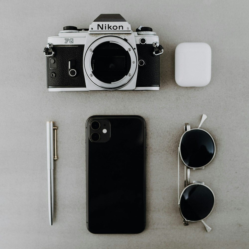 black and silver canon dslr camera beside white iphone 4 and black iphone 5