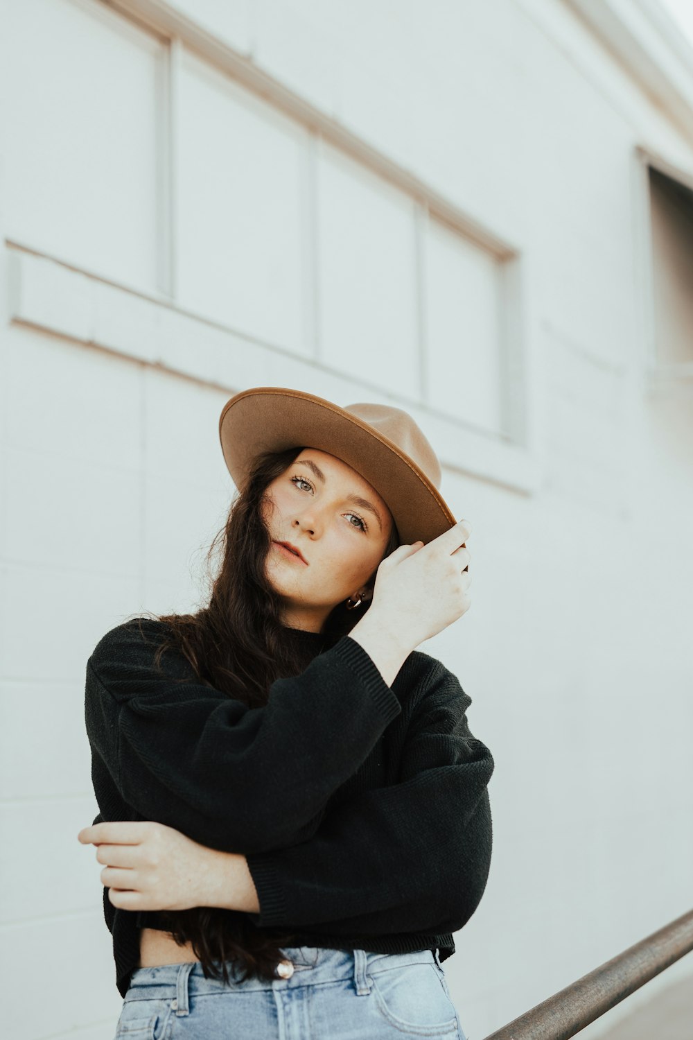 茶色のフェドーラ帽をかぶった黒い長袖シャツの女性