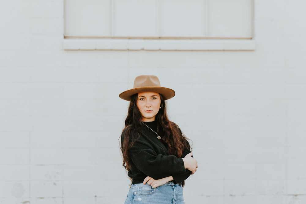 woman in black long sleeve shirt and blue denim jeans wearing brown hat