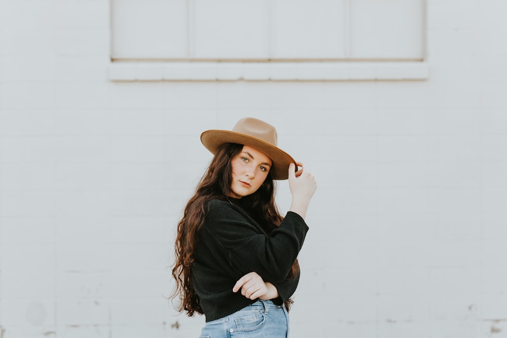 woman in black long sleeve shirt and blue denim jeans wearing brown cowboy hat