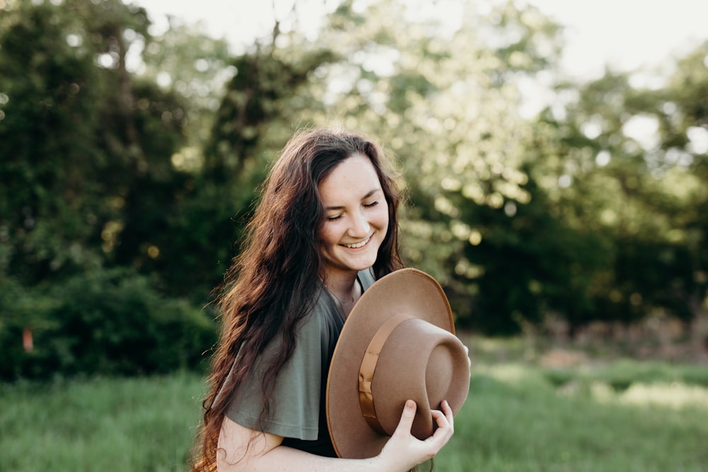 woman in black shirt holding brown hat