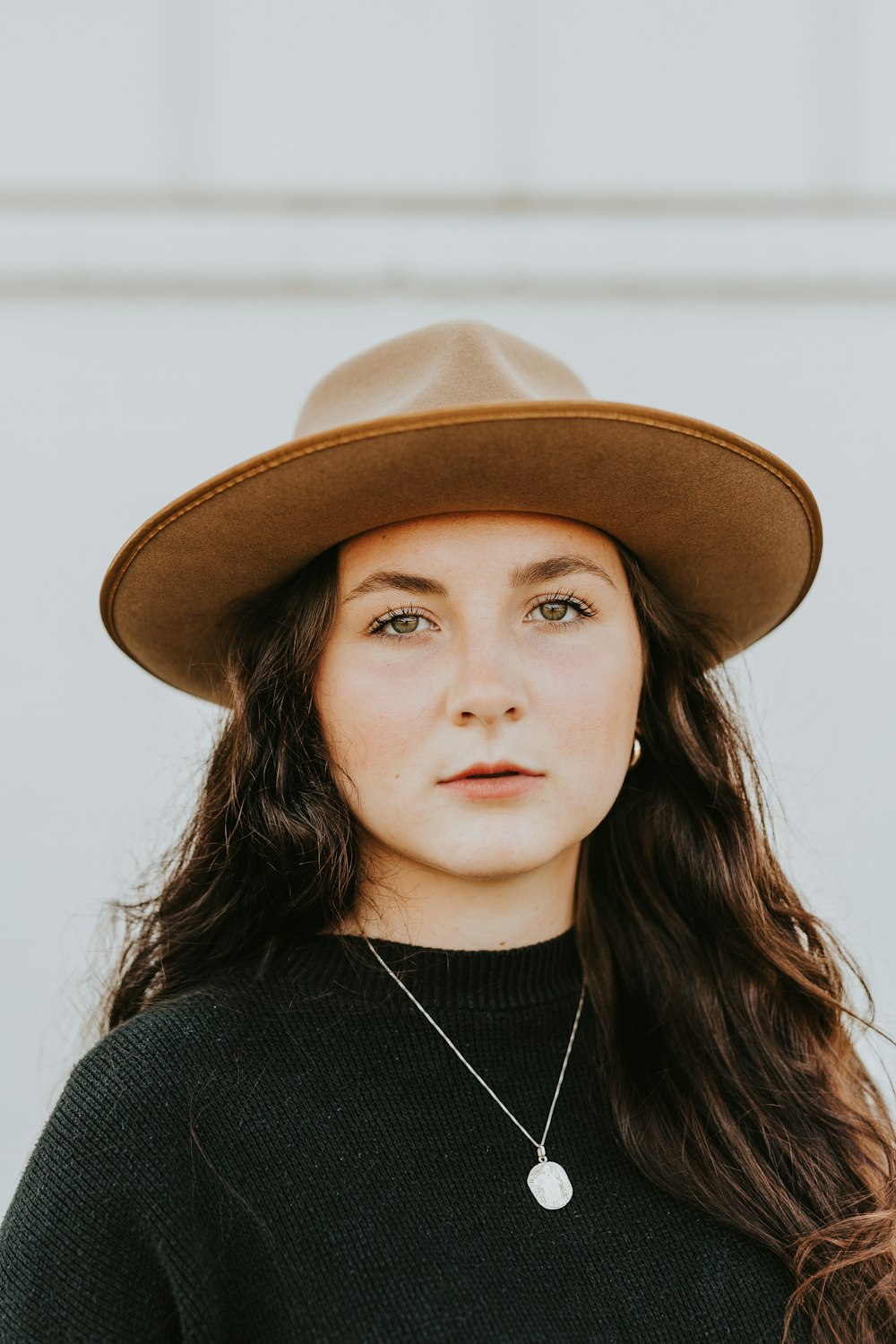 woman in black crew neck shirt wearing brown fedora hat