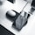 A smartphone is placed on a wireless charging pad along with a pair of white earbuds in their case. The sleek, modern setup is on a white desk surrounded by monitors and speakers, emphasizing a minimalistic and tech-savvy environment.