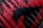 A section of corrugated metal covered in red and black spray paint, with the paint pattern resembling abstract shapes or perhaps an animal silhouette. The red paint is applied unevenly, allowing the dark color of the metal to show through in places, creating a distressed and textured appearance.