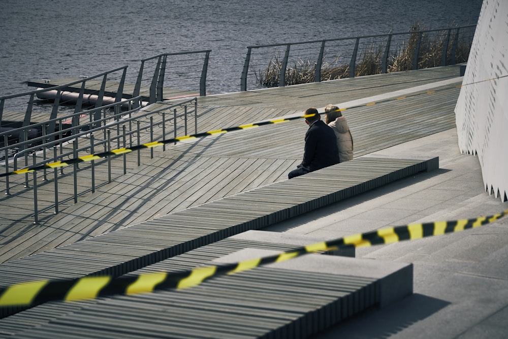 man and woman walking on gray wooden dock during daytime