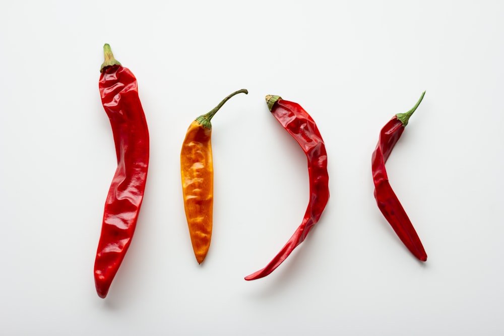 3 red chili peppers on white surface