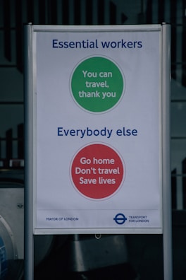 A sign with messages for different groups during the COVID-19 pandemic. The top section, with a green circle, is for essential workers and reads 'You can travel, thank you.' The bottom section, with a red circle, targets everybody else with the message 'Go home, Don't travel, Save lives.' It includes branding for the Mayor of London and Transport for London.