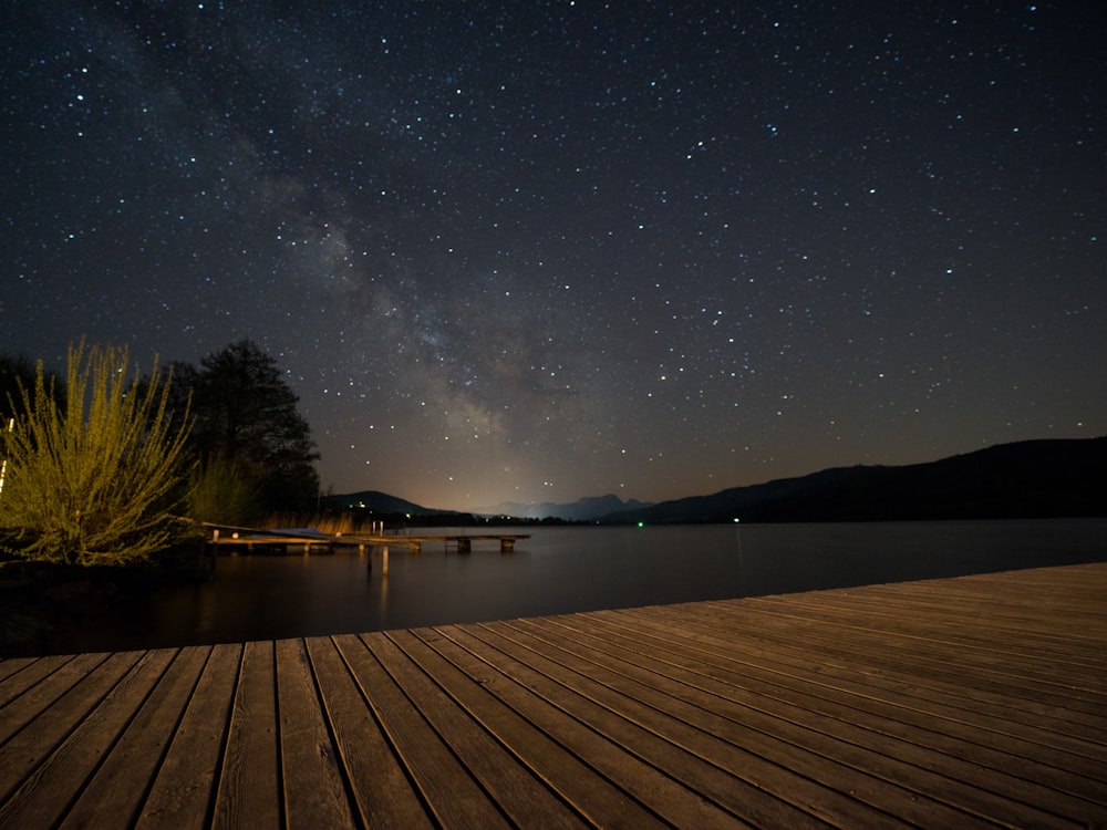 brown wooden dock on lake during night time