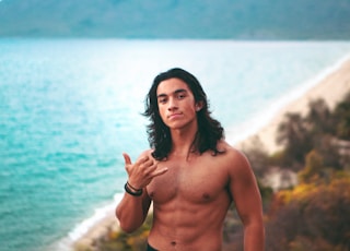 topless man in black shorts standing near body of water during daytime