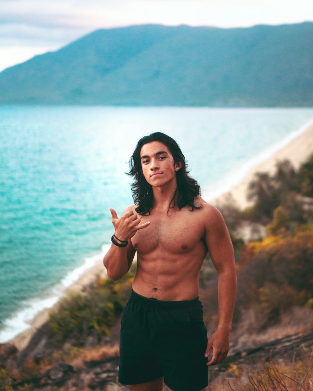 topless man in black shorts standing near body of water during daytime