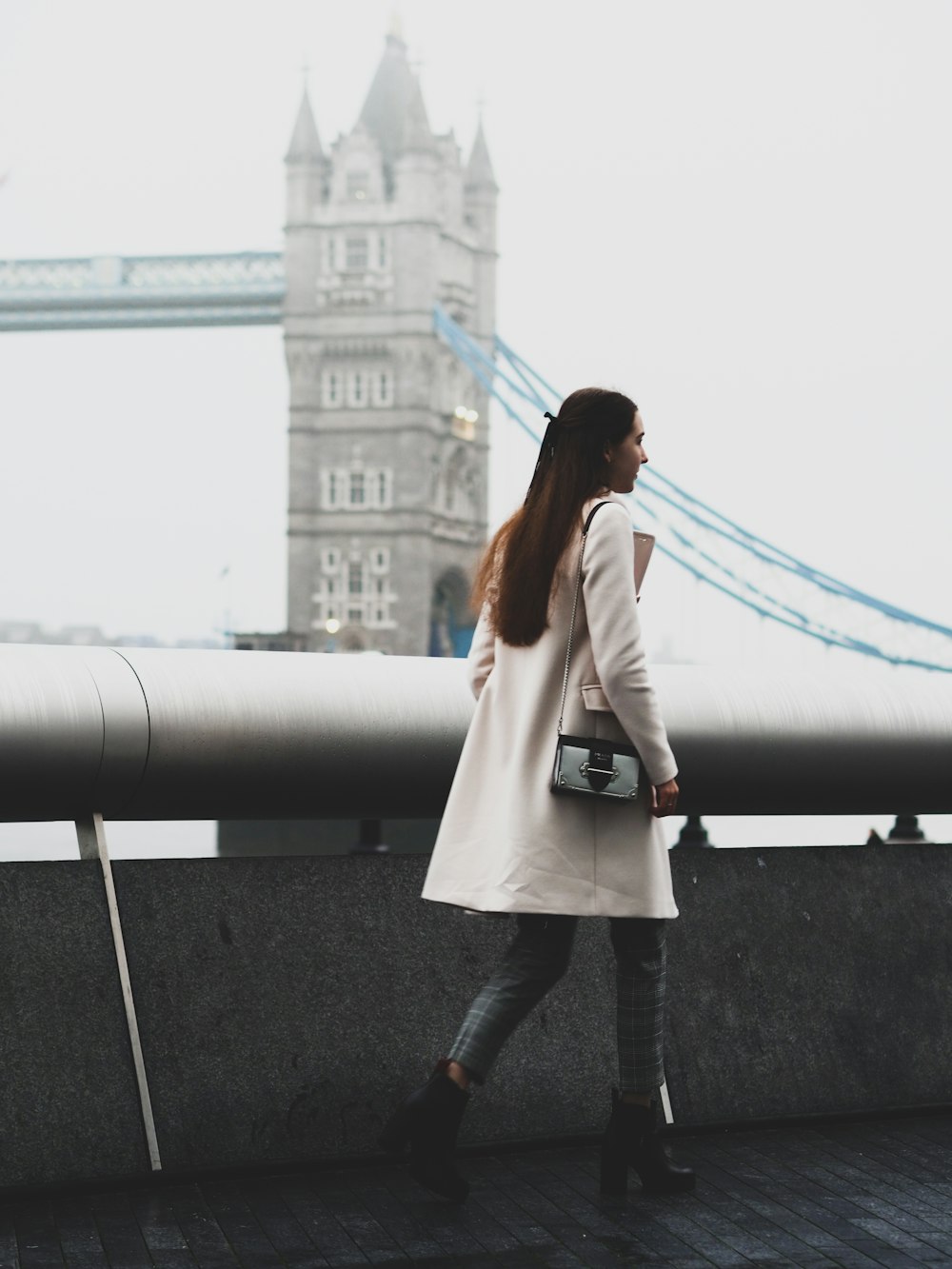 woman in white coat standing on gray concrete road during daytime