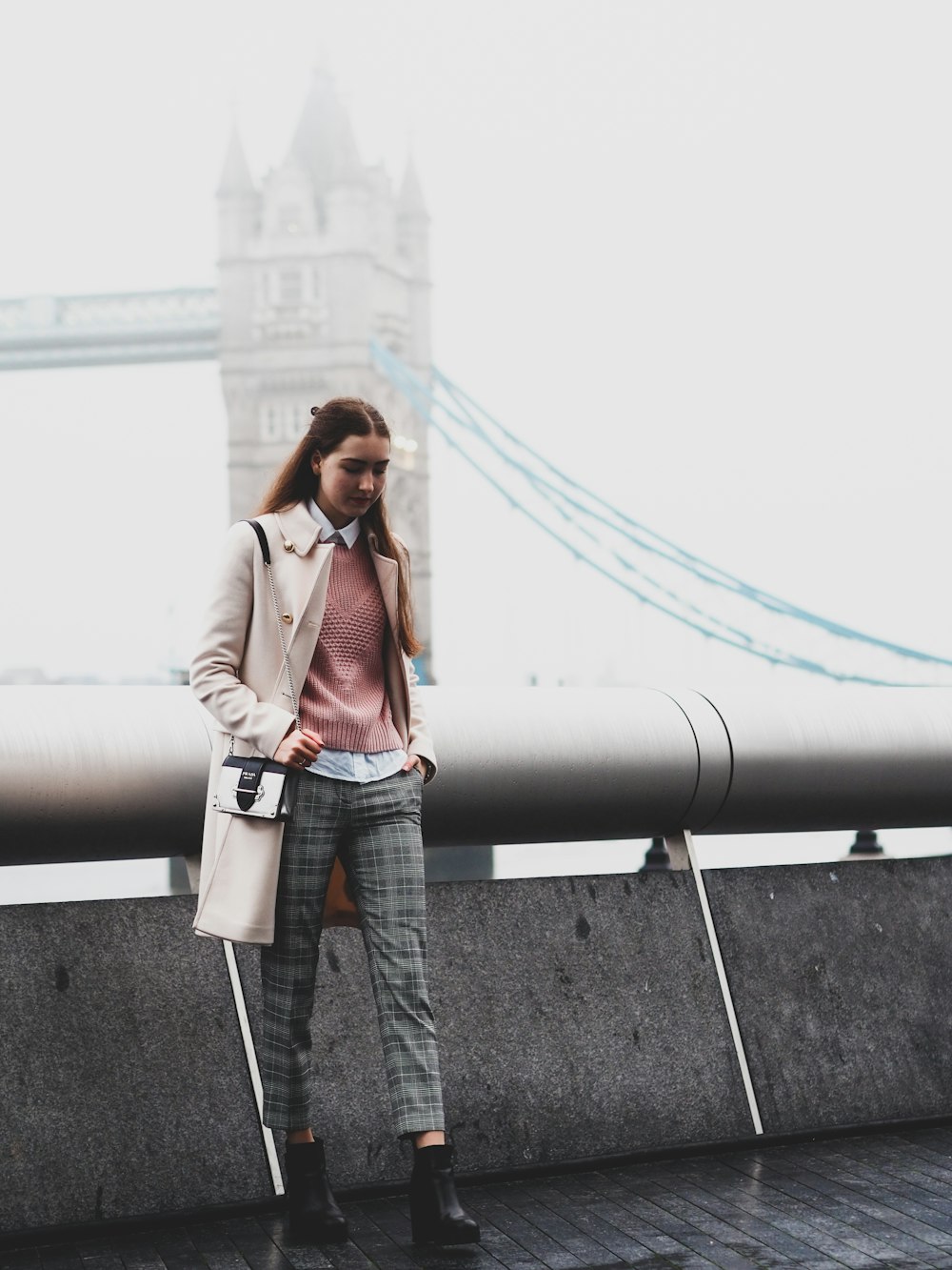 woman in brown coat standing on gray concrete floor during daytime