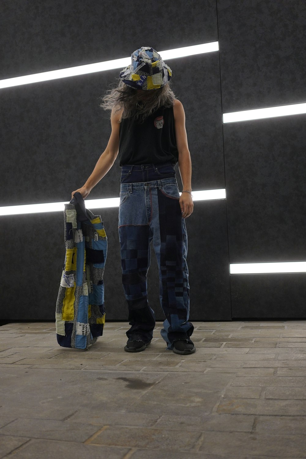 woman in black tank top and blue denim jeans standing beside black wall