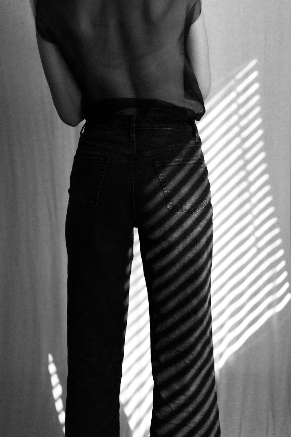 woman in black tank top and black pants standing near window