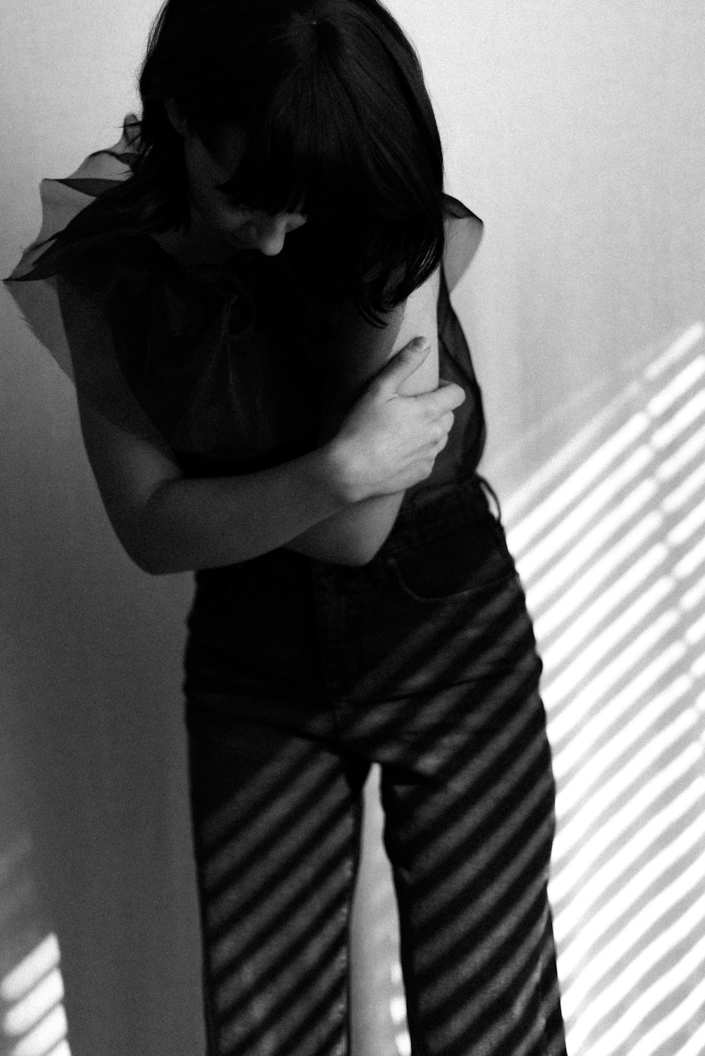 grayscale photo of woman in tank top covering her face with her hands