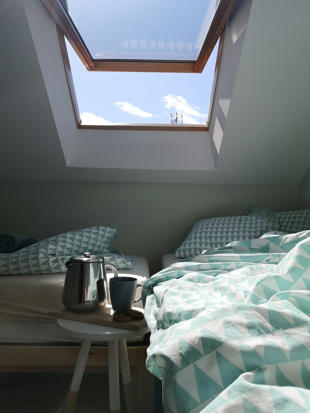 white and black ceramic mug on white and blue floral bed linen