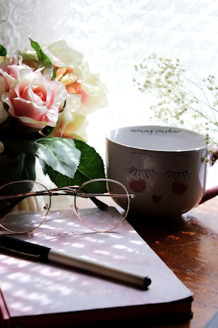 A cozy corner with a journal, coffee, and a bouquet of flowers.