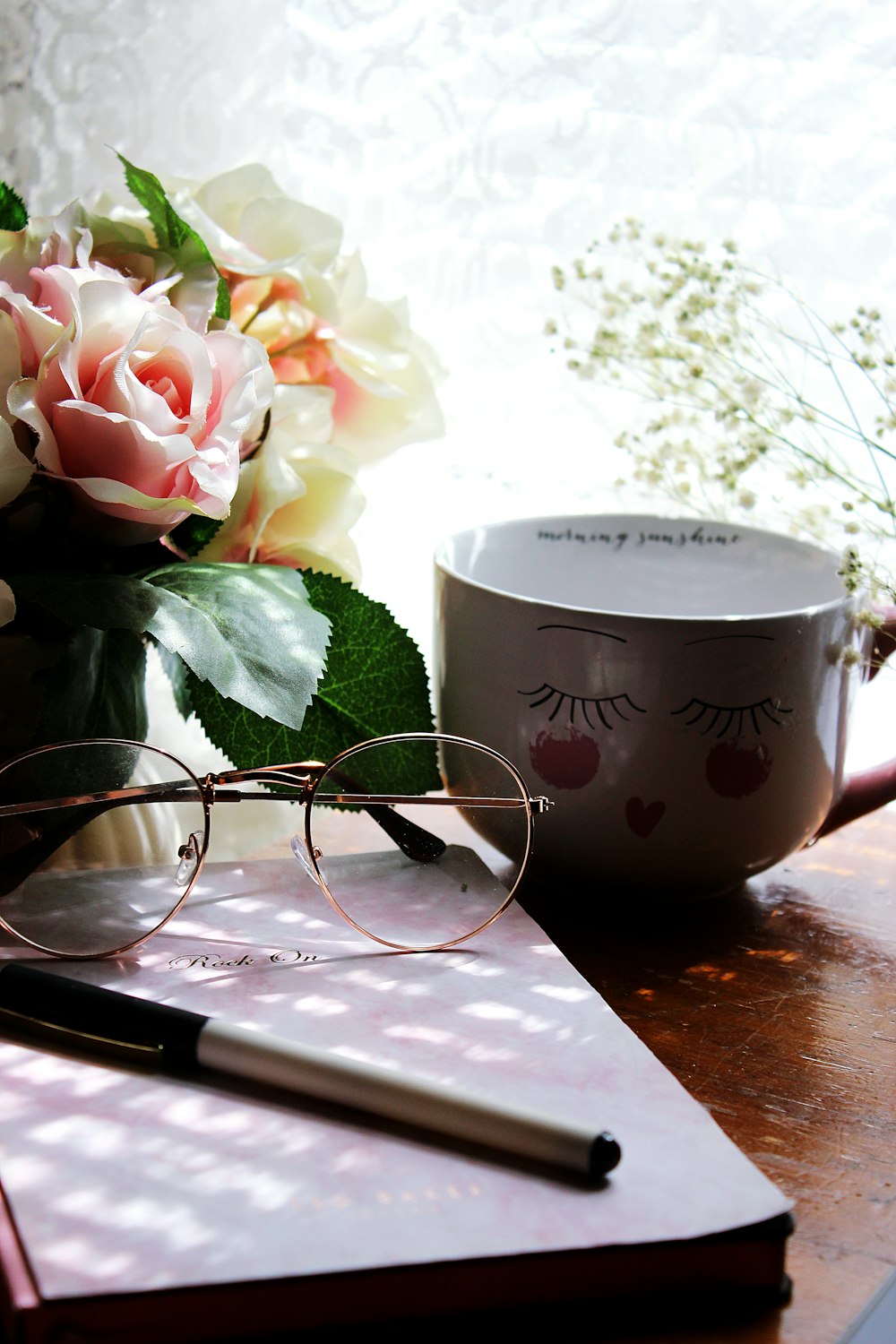 silver framed eyeglasses beside white and pink floral ceramic mug