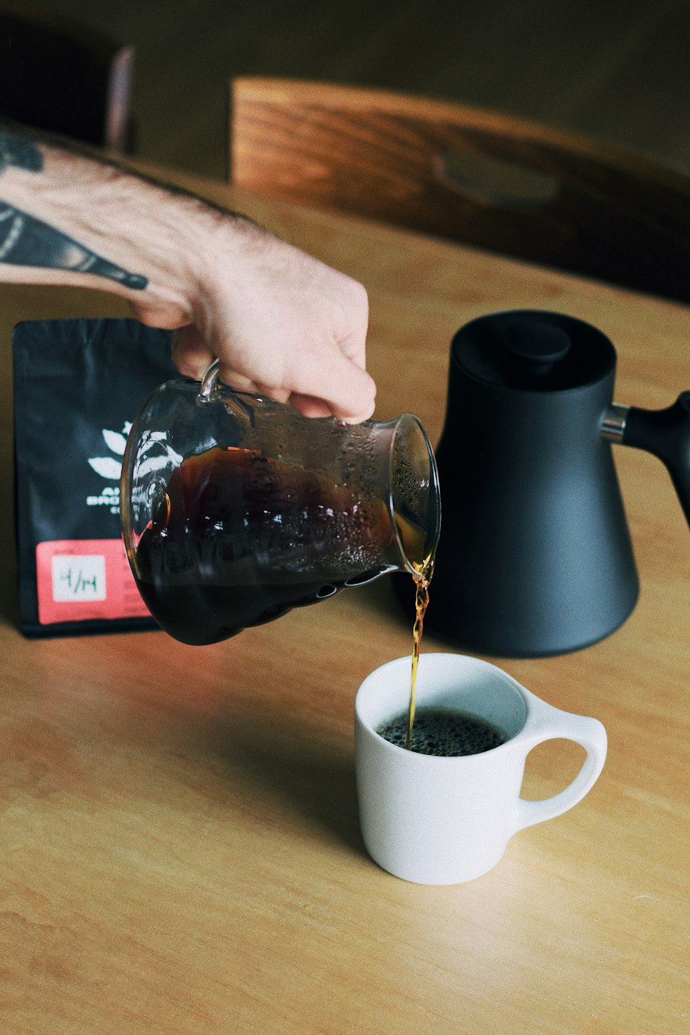 person holding clear glass mug with brown liquid