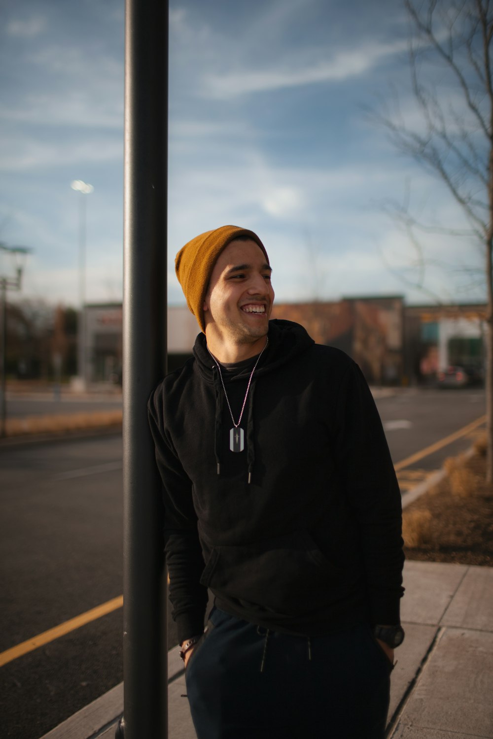 man in black zip up jacket standing near gray metal post during daytime