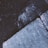 The image depicts a close-up view of a textured concrete surface with chalk markings or writings. There is a prominent crack running through the concrete, adding a sense of ruggedness. The lighting is dim, and the colors are predominantly cool tones, giving it a moody atmosphere.
