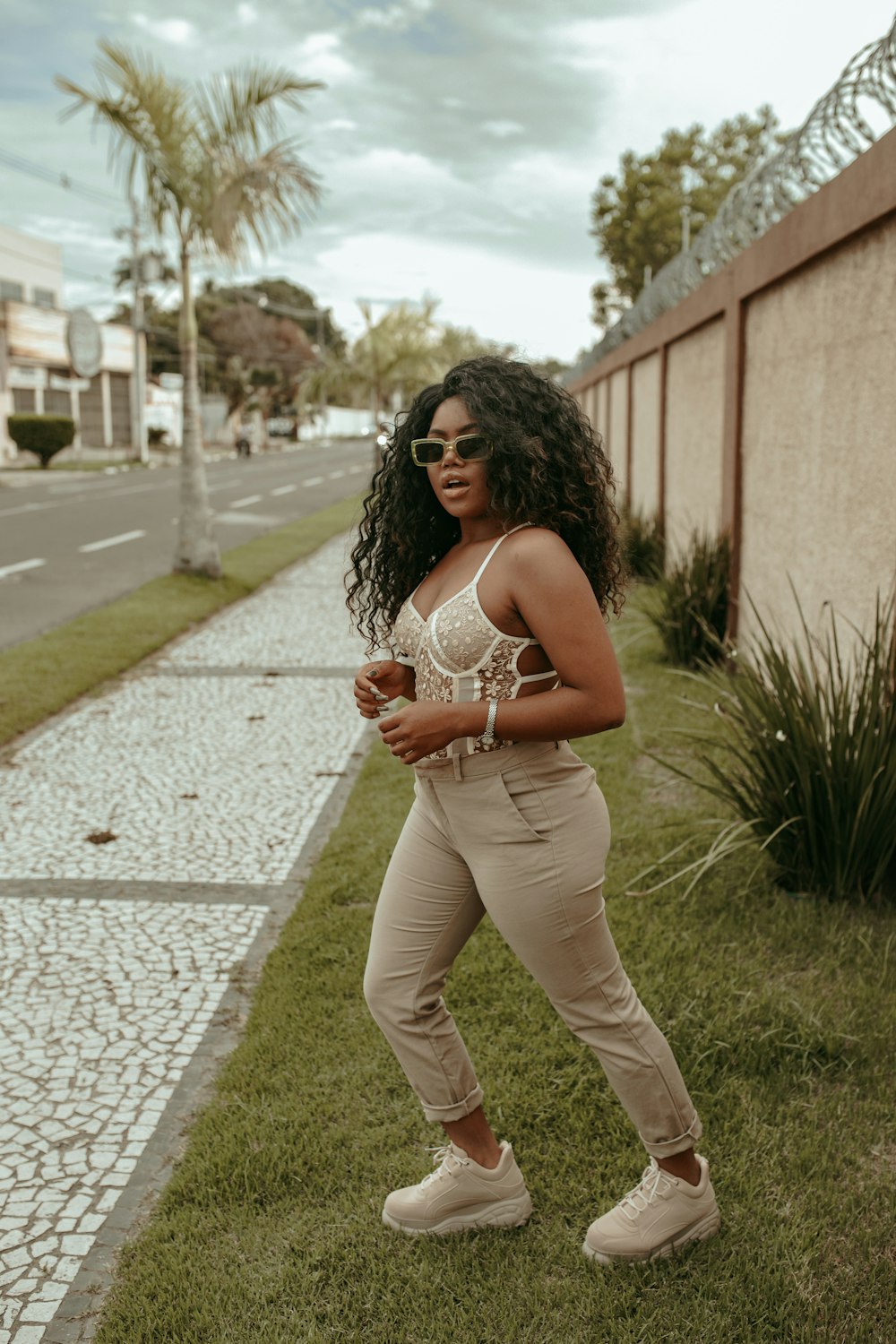 woman in white tank top and white pants standing on pathway during daytime