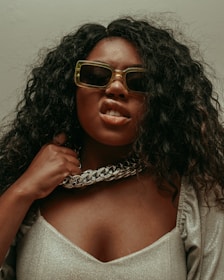 woman in white and black shirt wearing brown framed sunglasses
