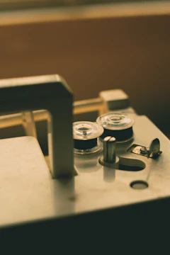 Vintage sewing machine with fabric swatches and spools of thread in soft gold and dusty rose tones.