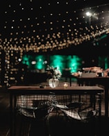 Soft glowing outdoor string lights draped above a rustic wooden garden table at dusk.