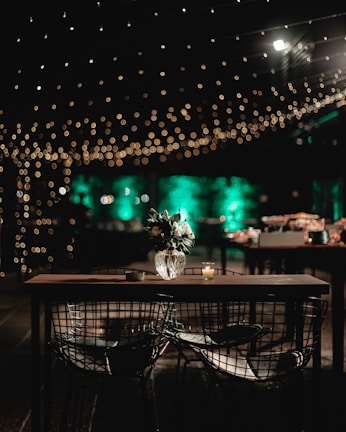 Close-up of a set of vintage-style chairs paired with a round table under soft string lights.