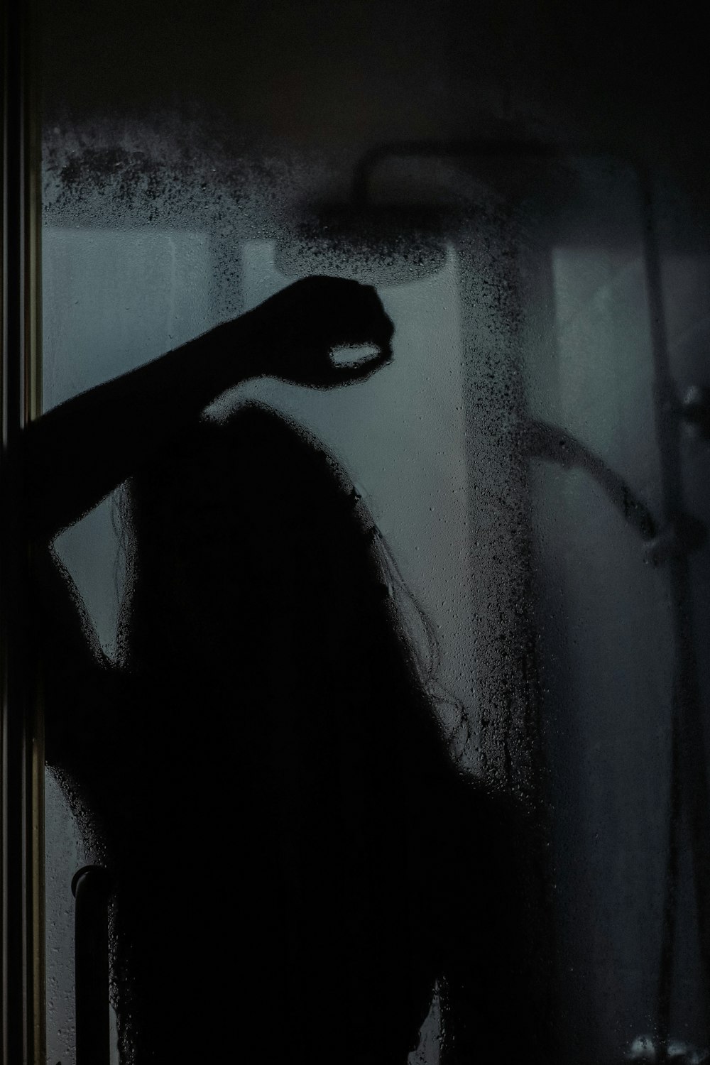 Mujer con camisa negra de manga larga de pie frente a una ventana de vidrio