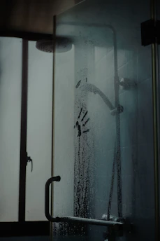 A close-up of a misty shower scene with droplets glistening on smooth tiles.
