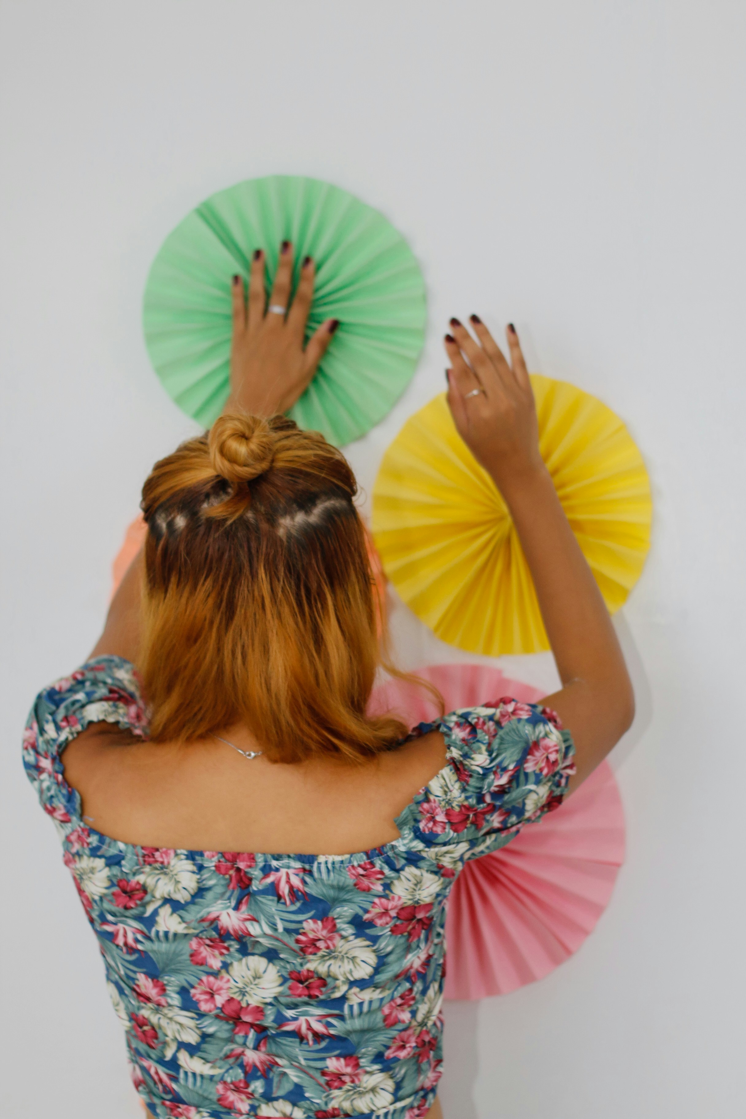 woman in white pink and green floral dress covering her face with her hands