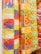 Colorful woven fabric rolls featuring intricate patterns and bright geometric designs. The fabrics display a mix of red, yellow, blue, and orange hues with various shapes such as diamonds and lines, creating a vibrant appearance.
