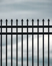 Wide shot of a custom iron enclosure with vertical bars surrounding a residential porch.