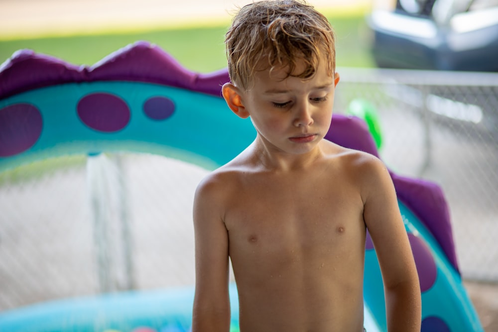 topless boy standing near swimming pool during daytime