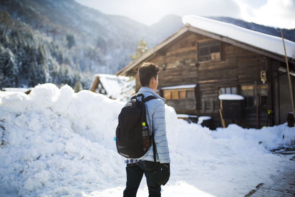 man in white jacket and black pants standing on snow covered ground during daytime