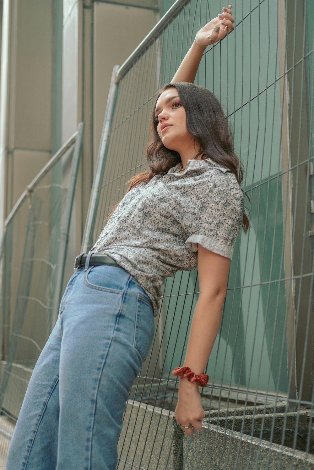 woman in white and black floral shirt and blue denim jeans standing near white wall during