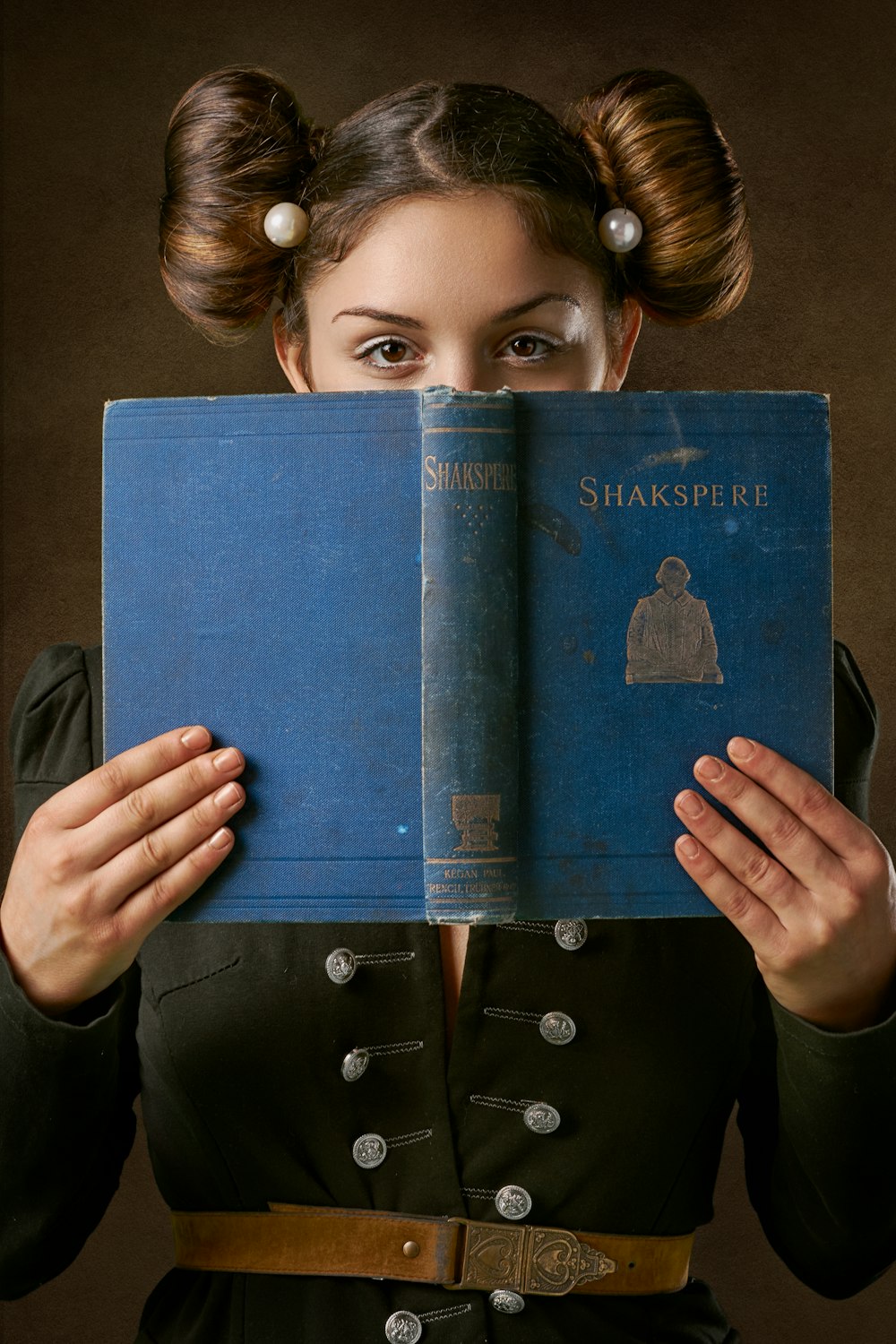 girl holding blue book on brown sofa