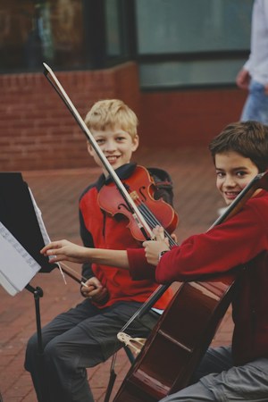 A young boy in a red shirt practices the violin, the kind of enrichment class smaller elementary schools work to keep as budgets tighten