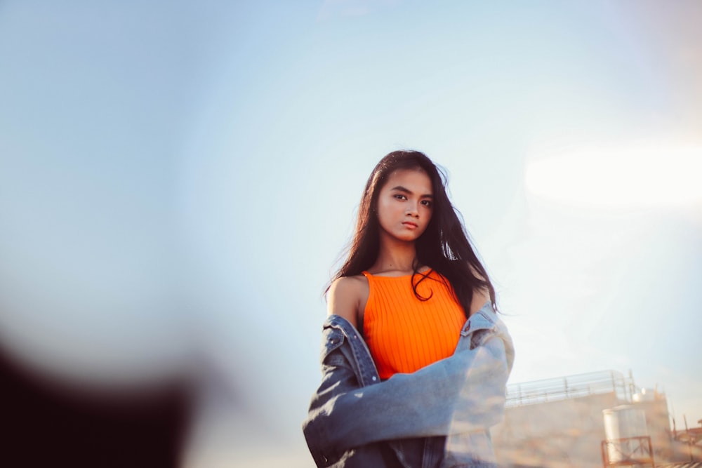 woman in orange tank top and blue denim jacket