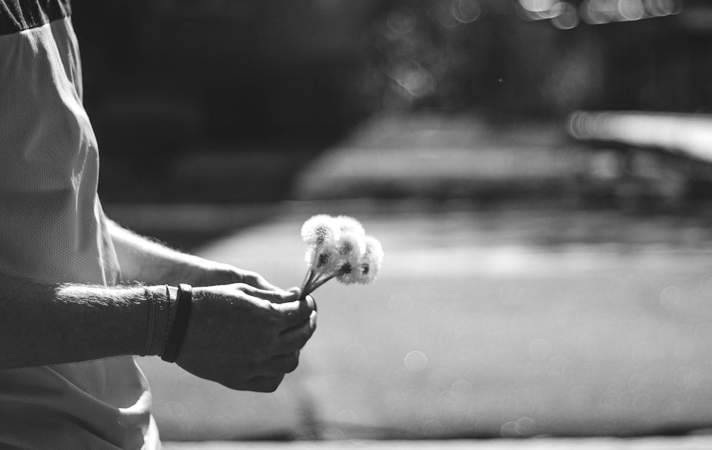 grayscale photo of person holding dandelion flower