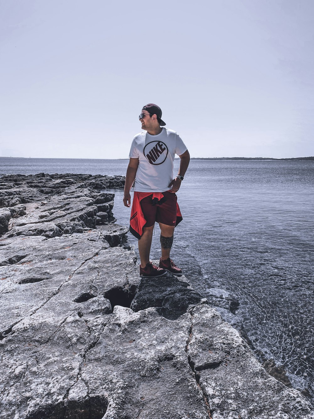 man in white crew neck t-shirt standing on rocky shore during daytime