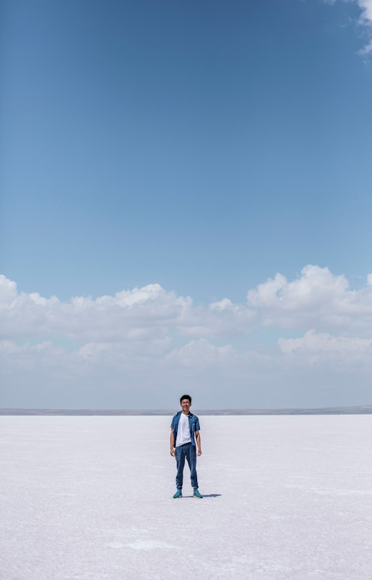man in white shirt and blue denim jeans standing on beach during daytime in Tuz Gölü Turkey