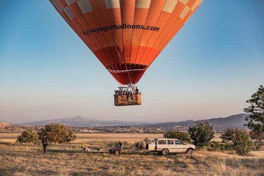 red hot air balloon on green grass field during daytime in Cappadocia Turkey