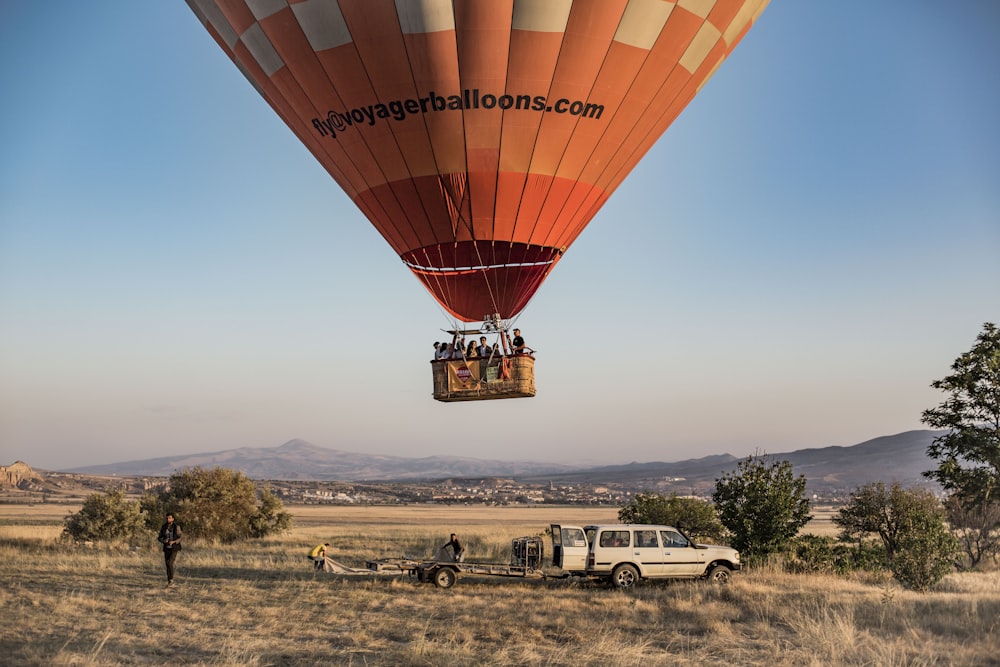 red hot air balloon on green grass field during daytime