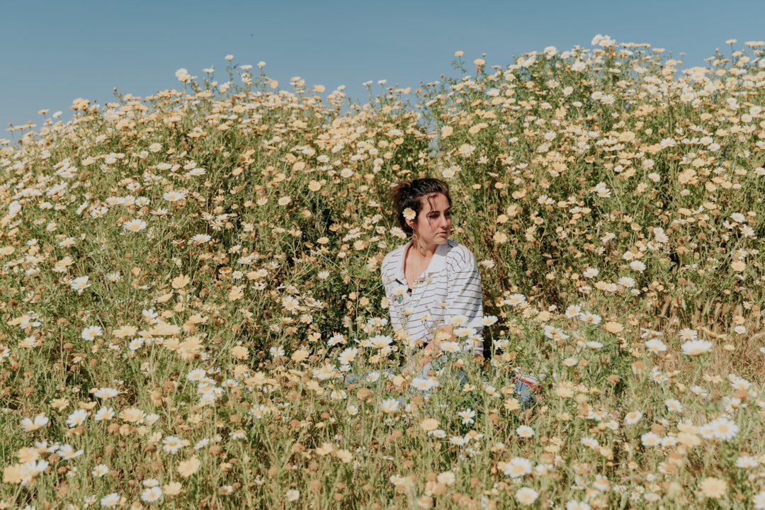 woman in white long sleeve shirt standing on white flower field during daytime